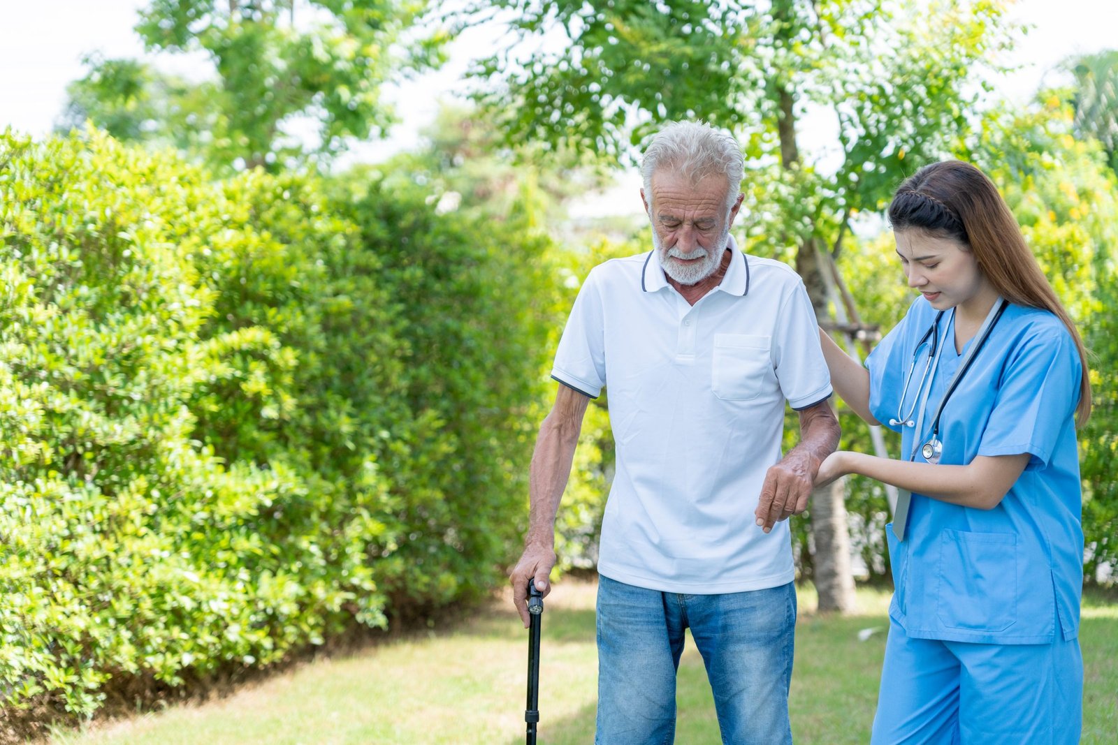 A nurse and a doctor supporting an older man as he walks during physical therapy.
